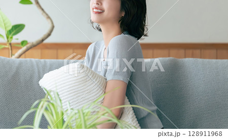 リビングのソファに座る笑顔の女性 リビングのソファに座る笑顔の女性 128911968