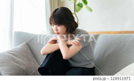 リビングのソファに座って考える女性 128911971