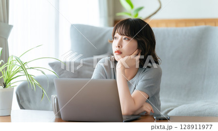 パソコンを使いながら考える女性 128911977