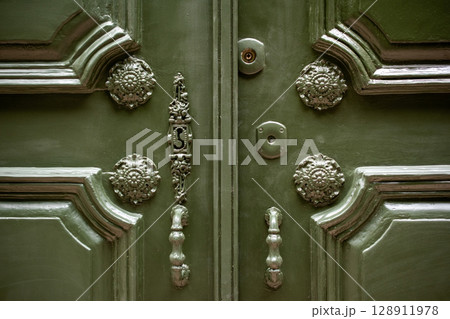 Close-up of an Antique Green Door with Ornate Hardware 128911978