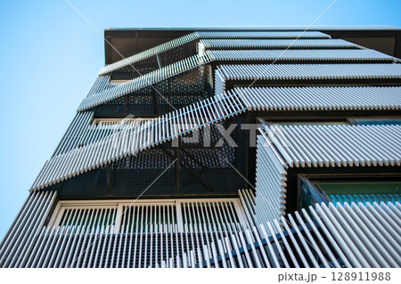 Modern Architectural Facade with Geometric Design and Blue Sky Modern Architectural Facade with Geometric Design and Blue Sky 128911988