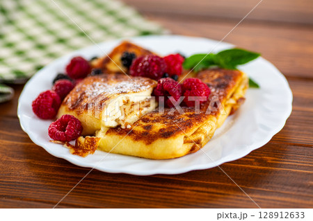 Golden cheese pancakes with berries on plate 128912633