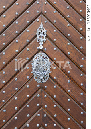 Old wooden door with metal decoration and rivets showing chevron pattern 128913469