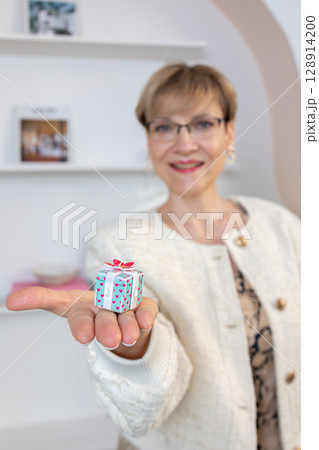 Woman hands holding gift box with red bow, close-up. Vertical photo. High quality photo 128914200