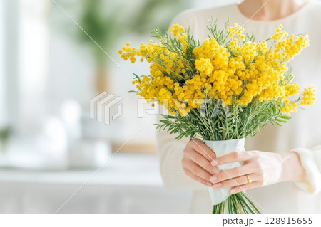 Woman enjoys a bouquet of mimosa flowers in a sunny, bright room filled with natural light and greenery. Generative AI 128915655