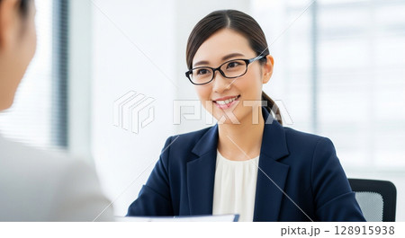 知的なリーダーシップ、眼鏡をかけた日本人女性が部下の報告を聞く 知的なリーダーシップ、眼鏡をかけた日本人女性が部下の報告を聞く 128915938