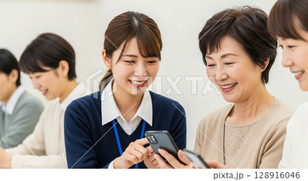 学ぶ喜びを再発見、笑顔でスマートフォン操作を教わるシニア 128916046