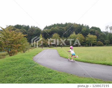 公園でキックボードで遊ぶ女の子 128917235