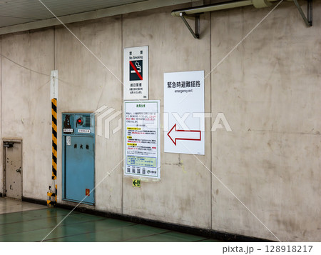 地下の鉄道駅構内に掲示された緊急時避難経路の案内表示 128918217
