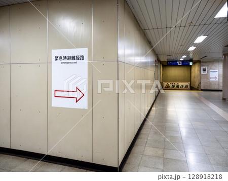 地下の鉄道駅構内に掲示された緊急時避難経路の案内表示 128918218