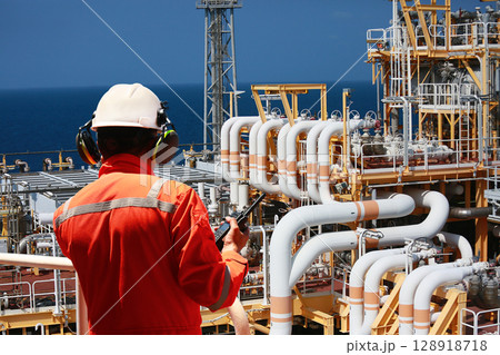 Technician monitor and command by radio to operator on job site in oil and gas industry, Worker in oil and gas industry contact to operation team to check condition of the machine, Maintenance work. 128918718