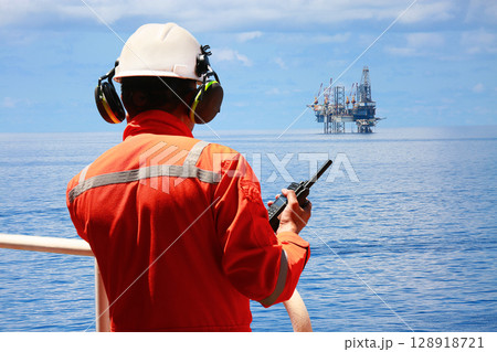 Technician monitor and command by radio to operator on job site in oil and gas industry, Worker in oil and gas industry contact to operation team to check condition of the machine, Maintenance work. 128918721
