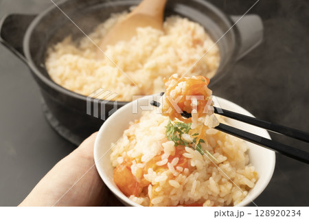 茶碗によそった土鍋で炊いた丸ごとトマトの炊き込みご飯を箸で持ち上げる 128920234