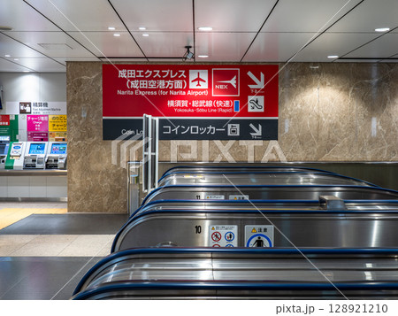 成田エクスプレスが発着するホームへ下りるエスカレーターと案内表示（JR東京駅） 128921210