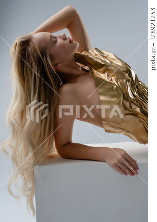 Beauty and elegance showcased in a studio with a blonde woman in a golden outfit 128921253