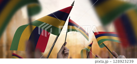 Mauritius flags in their hands on a blurred urban background 128923239