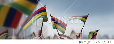 Mauritius flags in their hands on a blurred urban background 128923241