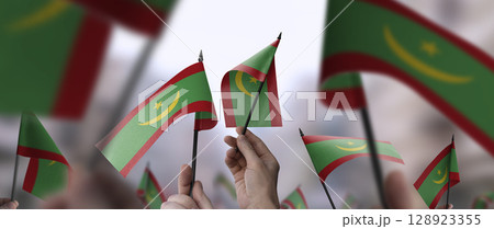 Mauritania flags in their hands on a blurred urban background 128923355