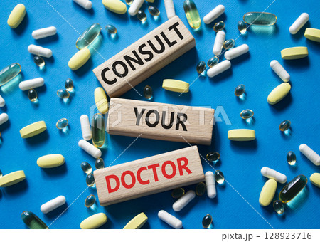 Consult Your Doctor symbol. Concept word Consult Your Doctor on wooden blocks. Beautiful blue background with pills. Medicine and Consult Your Doctor concept. Copy space Consult Your Doctor symbol. Concept word Consult Your Doctor on wooden blocks. Beautiful blue background with pills. Medicine and Consult Your Doctor concept. Copy space 128923716