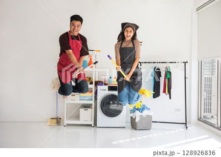Asian young couple ride mop and broomstick while jumping in air Asian young couple ride mop and broomstick while jumping in air 128926836