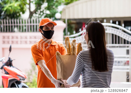 deliveryman give bouquet bread in paper bag to customer at front door 128926847