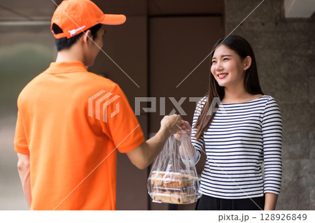 deliveryman in uniform give bakery to smiling Asian customer 128926849