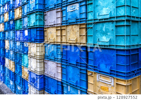 Stack of colorful plastic industrial crates arranged in a grid pattern for storage or transport use 128927552
