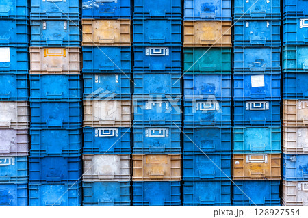 Stack of colorful plastic industrial crates arranged in a grid pattern for storage or transport use 128927554