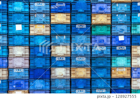 Stack of colorful plastic industrial crates arranged in a grid pattern for storage or transport use 128927555