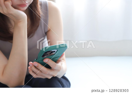 スマホを見て落ち込む女性 128928303