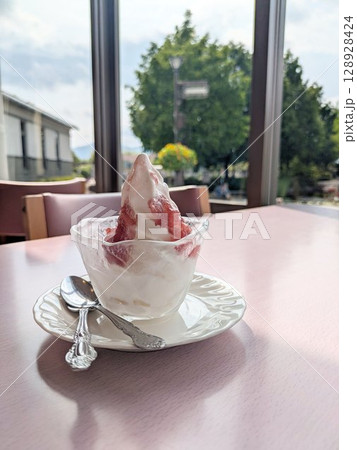 窓辺のテーブルに置かれた蓮の花ジャムがけソフトクリーム 128928424