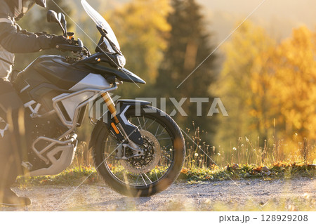 Driver posing on motorcycle during sunrise, rural countryside Driver posing on motorcycle during sunrise, rural countryside 128929208