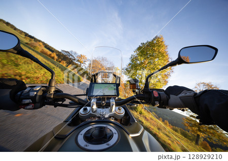 Driver riding motorcycle on empty road during sunset , view from the handlebars 128929210