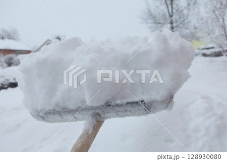 Snow shovel is holding a large pile of snow Snow shovel is holding a large pile of snow 128930080