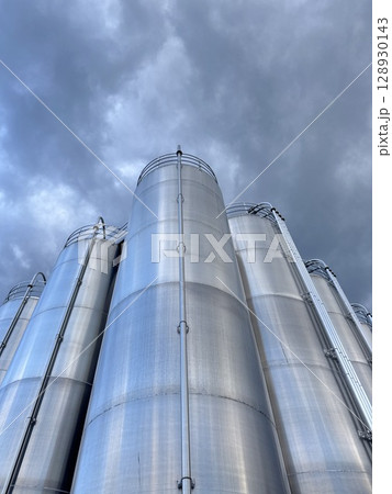 Large stack of silver tanks with a cloudy sky in the background Large stack of silver tanks with a cloudy sky in the background 128930143