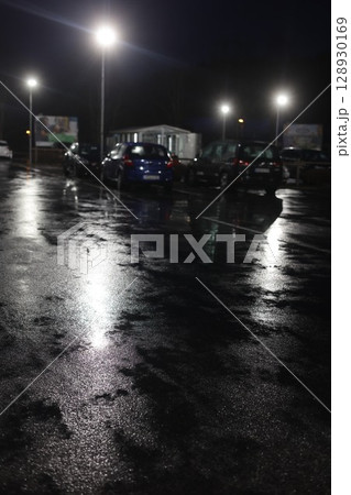 A parking lot with cars and a building in the background 128930169