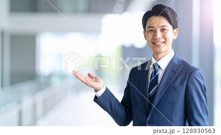 手を差し出して案内をする若いビジネスマン 128930563