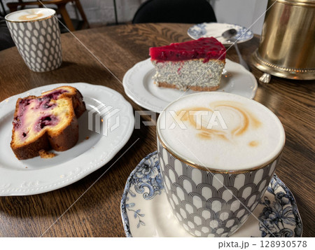 Coffee with heart foam and desserts on wooden table, featuring cakes in a cozy cafe setting 128930578