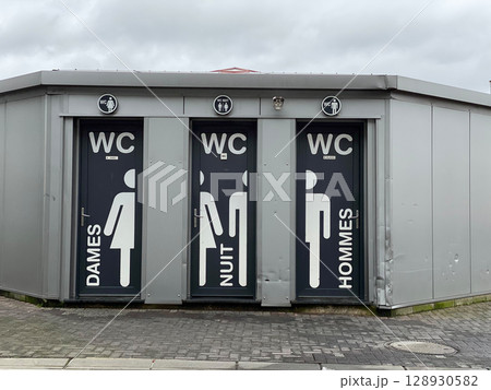 Public restroom with French signage on metallic building exterior against cloudy sky Public restroom with French signage on metallic building exterior against cloudy sky 128930582