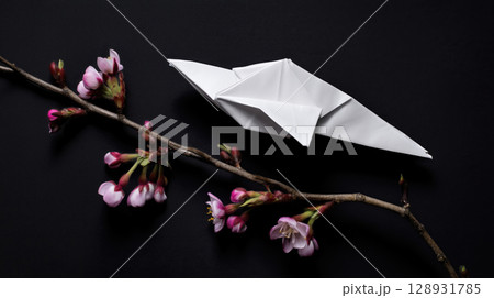 white origami paper bird rests on blossoming branch against black backdrop, evoking sense of peace and delicate beauty 128931785