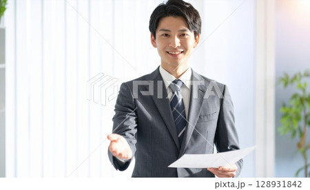 手を差し出して案内をする若いビジネスマン 手を差し出して案内をする若いビジネスマン 128931842