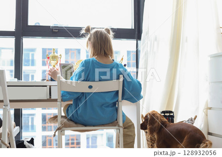 young girl seating at the table in your room near windows young girl seating at the table in your room near windows 128932056