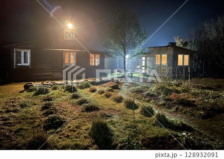 View of mysterious house with lit windows at night View of mysterious house with lit windows at night 128932091