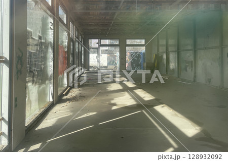 Abandoned industrial building with sunlight through window, empty interior Abandoned industrial building with sunlight through window, empty interior 128932092