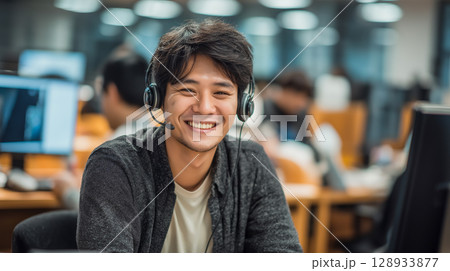 Happy Asian man working in call center office Happy Asian man working in call center office 128933877
