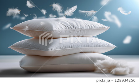 White pillows with floating feathers in a room 128934250