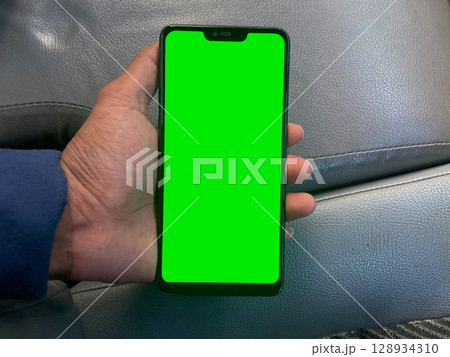 Smartphone with a green screen in the hands of a man. 128934310