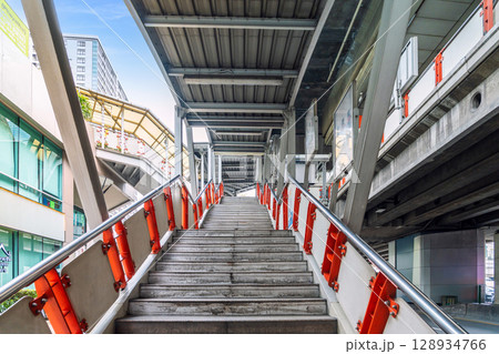 Urban pedestrian overpass with concrete stairs and metal roof structure in modern city environment 128934766