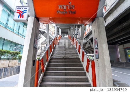 Urban pedestrian overpass with concrete stairs and metal roof structure in modern city environment 128934769