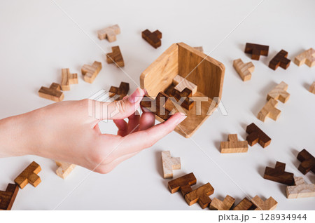 Female hand holding wooden puzzle for leisure thinking game 128934944